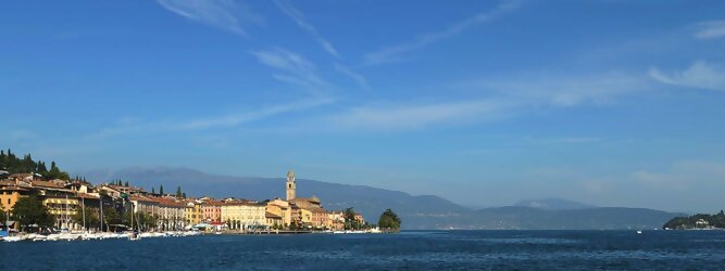 Trip Alpen beliebte Urlaubsziele am Gardasee -  Mit einer Fläche von 370 km² ist der Gardasee der größte See Italiens. Es liegt am Fuße der Alpen und erstreckt sich über drei Staaten: Lombardei, Venetien und Trentino. Die maximale Tiefe des Sees beträgt 346 m, er hat eine längliche Form und sein nördliches Ende ist sehr schmal. Dort ist der See von den Bergen der Gruppo di Baldo umgeben. Du trittst aus deinem gemütlichen Hotelzimmer und es begrüßt dich die warme italienische Sonne. Du blickst auf den atemberaubenden Gardasee, der in zahlreichen Blautönen schimmert - von tiefem Dunkelblau bis zu funkelndem Türkis. Majestätische Berge umgeben dich, während die Brise sanft deine Haut streichelt und der Duft von blühenden Zitronenbäumen deine Nase kitzelt. Du schlenderst die malerischen, engen Gassen entlang, vorbei an farbenfrohen, blumengeschmückten Häusern. Vereinzelt unterbricht das fröhliche Lachen der Einheimischen die friedvolle Stille. Du fühlst dich wie in einem Traum, der nicht enden will. Jeder Schritt führt dich zu neuen Entdeckungen und Abenteuern. Du probierst die köstliche italienische Küche mit ihren frischen Zutaten und verführerischen Aromen. Die Sonne geht langsam unter und taucht den Himmel in ein leuchtendes Orange-rot - ein spektakulärer Anblick.